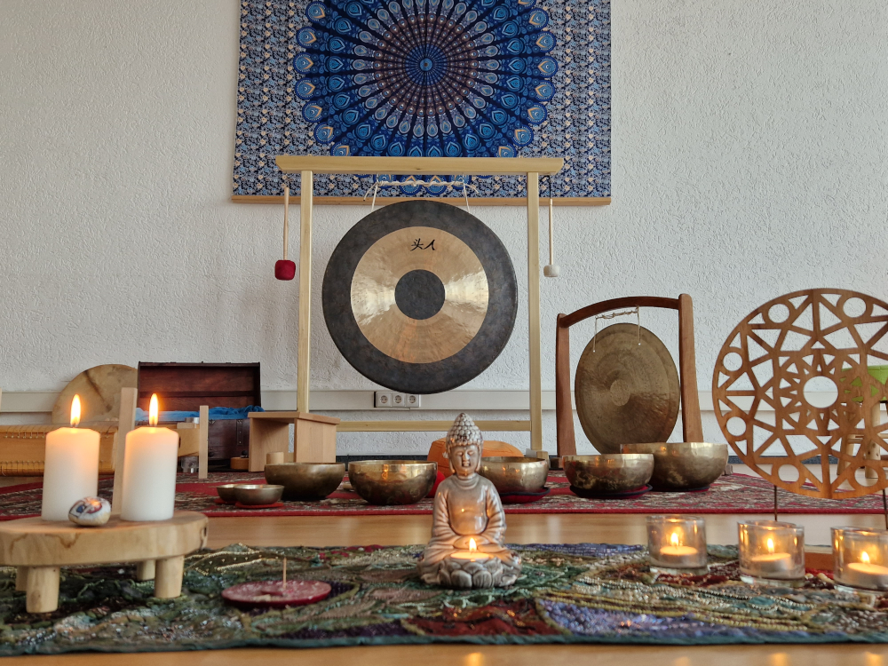 Meditativer Klangreise-Aufbau mit Buddhafigur, Kerzenlicht und Klanginstrumenten wie Gong und Klangschalen – Raum für Ruhe und tiefes Eintauchen